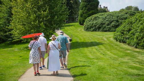 A group of adults walking along a path between mowed grass gardens and trees